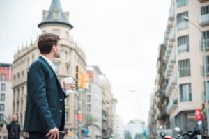 young-businessman-holding-coffee-cup-hand-looking-buildings-city